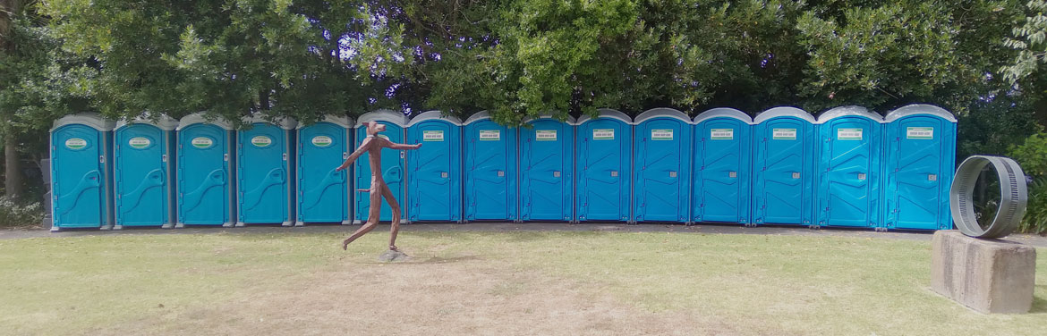 A line of blue portaloos lined up at an event